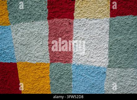 A close-up view of colorful textured plaster on an exterior house wall, highlighting the rough surface, irregular patterns, and varied tones of the fi Stock Photo