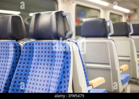Interior of a modern German passenger train with rows of blue upholstered seats and headrests, showing clean public transport seating and railway trav Stock Photo