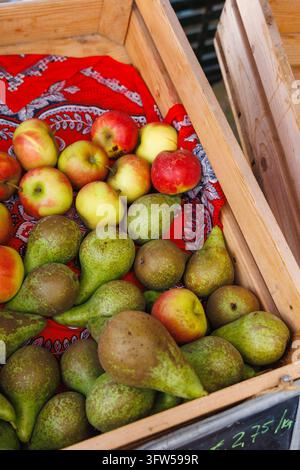 Ripe pears and red and yellow apples in a wooden crate at a farmers market stall Stock Photo