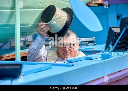 Man wearing glasses raises his hat from inside a blue parade float at the daytime Three Kings Parade in Almunecar, Spain. Stock Photo