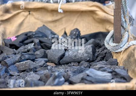 Close view of black coal pieces in a burlap lined parade cart with rope detail. Almunecar, Spain, January 6, 2026. Stock Photo