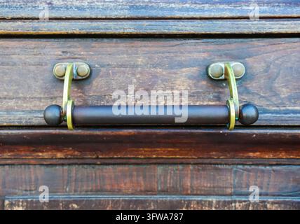 Ornate brass handle mounted on an aged wooden door, showing texture and detail Stock Photo