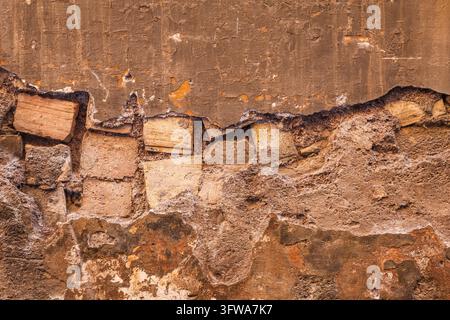 Old wall texture showing layers of damaged plaster and exposed bricks Stock Photo