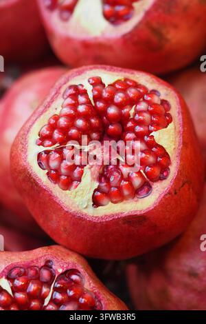 Cut pomegranates show clusters of seeds at a market stall Stock Photo