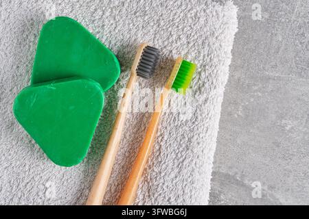 Eco friendly composition with solid shampoo pieces and bamboo toothbrushes on soft white towel Stock Photo