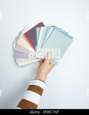 Hand holding color swatches for wall painting, choosing paint shade for home makeover, renovation and interior decoration concept Stock Photo