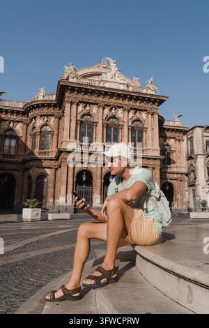 Young male tourist using a smartphone in a historic city square Stock Photo