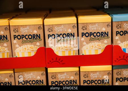 RIGA, LATVIA. 12th March 2026. Boxes of Snack Day butter flavour popcorn stacked neatly on display shelves in a supermarket in Riga, Latvia. Stock Photo