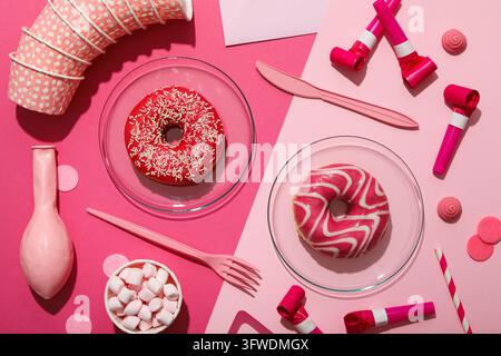Donuts, marshmallows and party supplies on pink background, top view Stock Photo