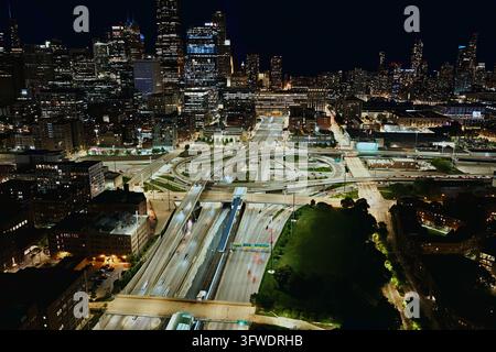 Aerial night view down the illuminated expressway into the Jane Byrne Interchange west of downtown with the skyline lit up behind, Chicago, Illinois Stock Photo