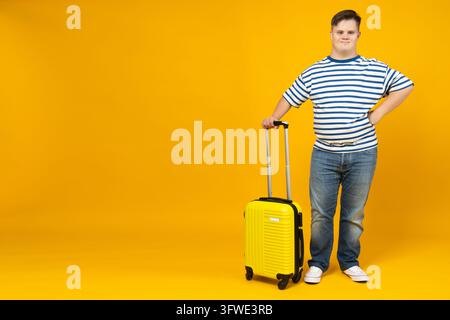 Smiling young man with down syndrome with suitcase, place for text Stock Photo