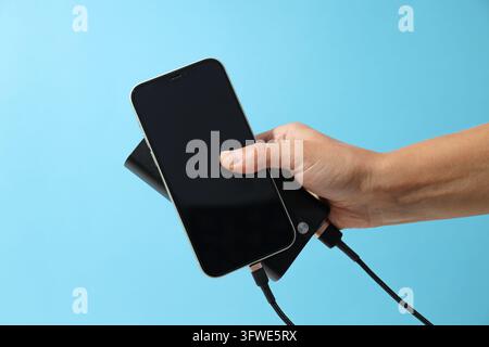 Powerbank and smartphone in hand on blue background Stock Photo