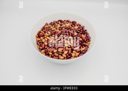 White ceramic bowl filled with mixed red and speckled tan dried beans shown from top-down three-quarter view, studio still life on Stock Photo