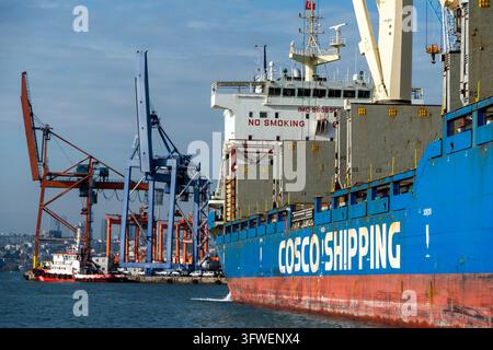 Wire Model Ship A COSCO Shipping cargo ship sits at a dock with cranes nearby in ...