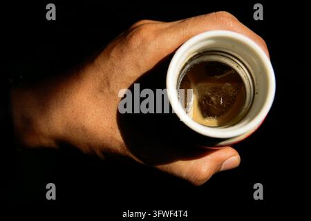 Close up of hand holding ice coffee latte on 14 oz tumbler isolated on black background Stock Photo