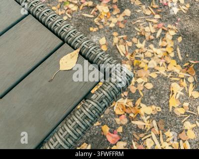 Single yellow autumn leaf on rattan table top view in garden setting Stock Photo