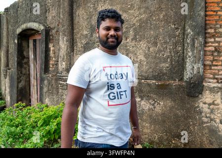 Smiling man in a white t-shirt in front of an old stone wall, Southern Province, Galle, Sri Lanka Stock Photo