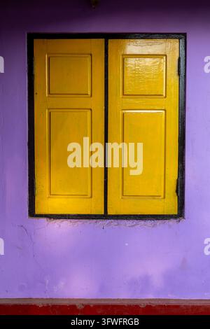 Yellow wooden window shutters on a purple wall, Northern Province, Mannar, Sri Lanka Stock Photo