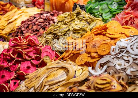 Colorful piles of dehydrated exotic fruits including kiwi, apples, bananas, persimmons, and coconut slices at a traditional market display in Istanbul Stock Photo