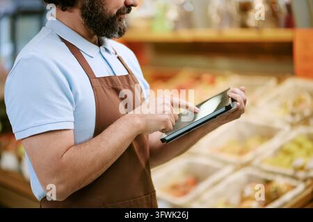 Man Using Digital Tablet for Inventory Management in Supermarket Stock Photo