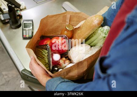 Man Holding Paper Bag with Fresh Groceries at Supermarket Checkout Stock Photo