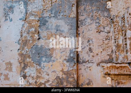 Abstract Full Frame Background Texture of Old Sun-Dried Limestone Wall Showing Layers of Flaking Paint, Cracks and Carved Molded Stone Detail Stock Photo