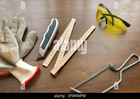 DIY home improvement tools and protective gear on wooden workshop table. Handyman craft hobby maker kit for apartment repair. Self made domestic Stock Photo