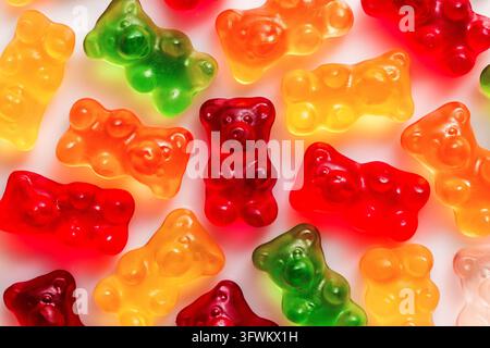 Red gummy bear centered among colorful gummy candies on a white background macro top view Stock Photo