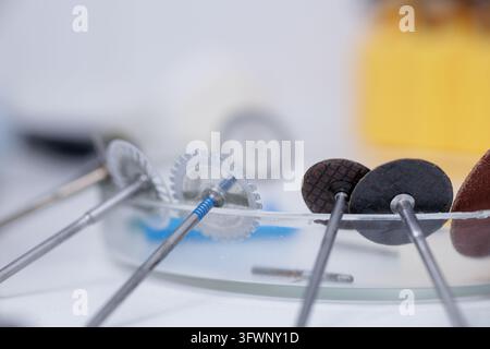 Dental rotary burs and milling cutters arranged on a reflective tray for prosthodontic laboratory work, illustrating precision tools used in Stock Photo