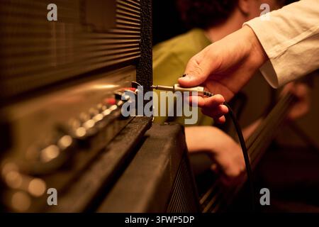 Teenager Plugging Audio Cable into Amplifier during Rehearsal Stock Photo
