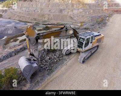 Aerial view of a yellow excavator working in a stone mine in Poland. Stock Photo