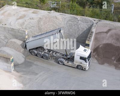 White dump truck dumping sand and soil material at an outdoor ...