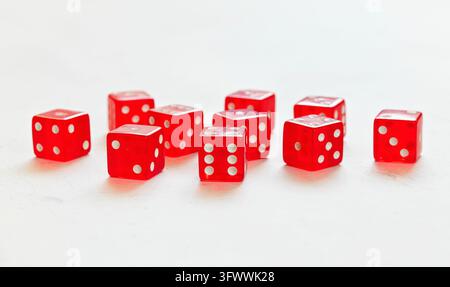 Ten red translucent craps dices on white board showing different numbers Stock Photo