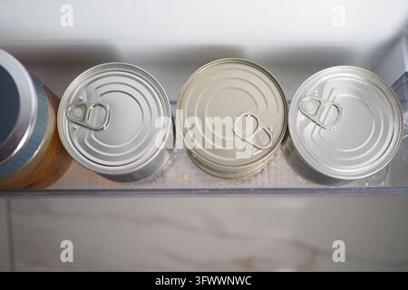 Three pull-tab cans stored in a refrigerator door shelf Stock Photo