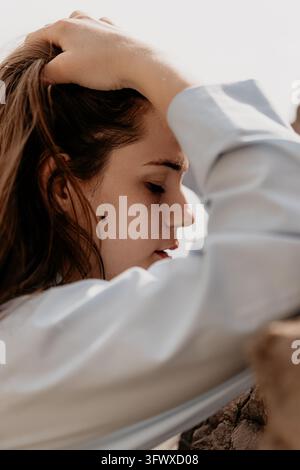 Woman profile portrait young female with closed eyes touching hair in outdoor setting during daylight Stock Photo