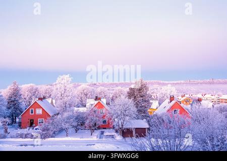 Scenic winter cityscape featuring red detached houses surrounded by snow and frost covered trees Stock Photo