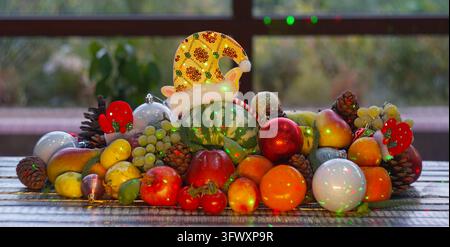 A high-quality horizontal eye-level shot of a festive Christmas arrangement, featuring a small green striped watermelon in a glowing yellow holiday el Stock Photo