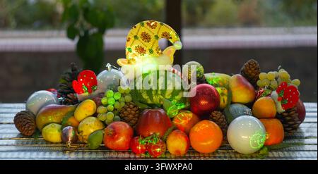 A high-quality horizontal eye-level shot of a festive Christmas arrangement, featuring a small green striped watermelon in a glowing yellow holiday el Stock Photo