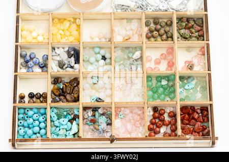 A wooden organizer holds many colorful gemstone beads Stock Photo