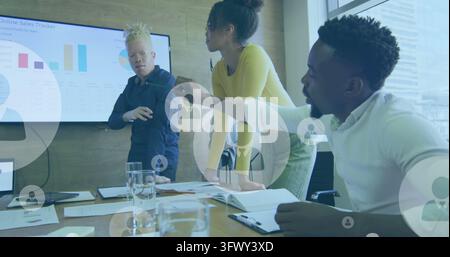 Image of profile icons floating against diverse colleagues discussing together at office Stock Photo