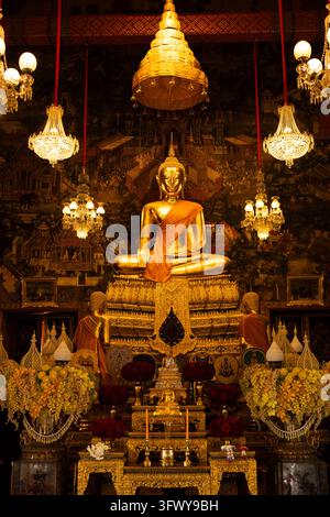 Bangkok, Thailand - February 1, 2026: A large golden Buddha statue sits in a meditative pose within an ornate temple interior, surrounded by... Stock Photo