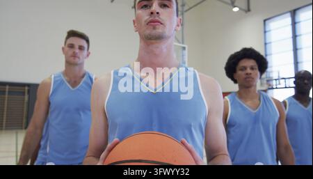 Portrait of diverse male basketball team with ball on indoor court Stock Photo