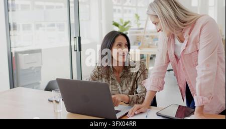 Diverse female colleagues using laptop and discussing work at office Stock Photo