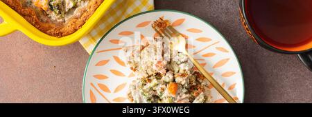 A slice of gluten-free pie sits on a plate beside a fork. The pie is made with red fish and broccoli, perfect for a healthy breakfast or lunch. A cup Stock Photo