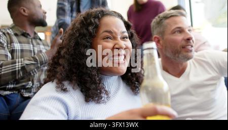 Happy diverse male and female friends watching sport on tv and celebrating victory Stock Photo