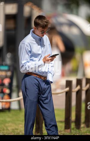 Brickell, FL, USA - October 20, 2026: Handsome young businessman on his phone in a blue shirt and blue pants photographed on the streets of Brickell M Stock Photo