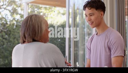 Smiling young man engaging in conversation with senior woman in bright room Stock Photo