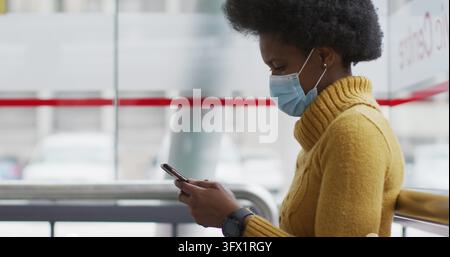 African american businesswoman with face mask using smartphone Stock Photo