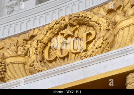 Moscow, Russia, 26 09 2026: Close-up of gilded architectural decoration featuring the Cyrillic USSR inscription, a five-pointed star, wheat ears and o Stock Photo