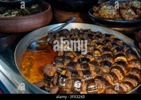 Izmir, turkey, august 8, 2025. Patlican dizme, layers of eggplant and meatballs simmering in rich tomato sauce at a traditional food market in izmir, Stock Photo